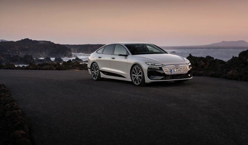 Audi A6 Sportback e-tron'un deniz kıyısındaki kayalıklar önünde duran beyaz bir örneği