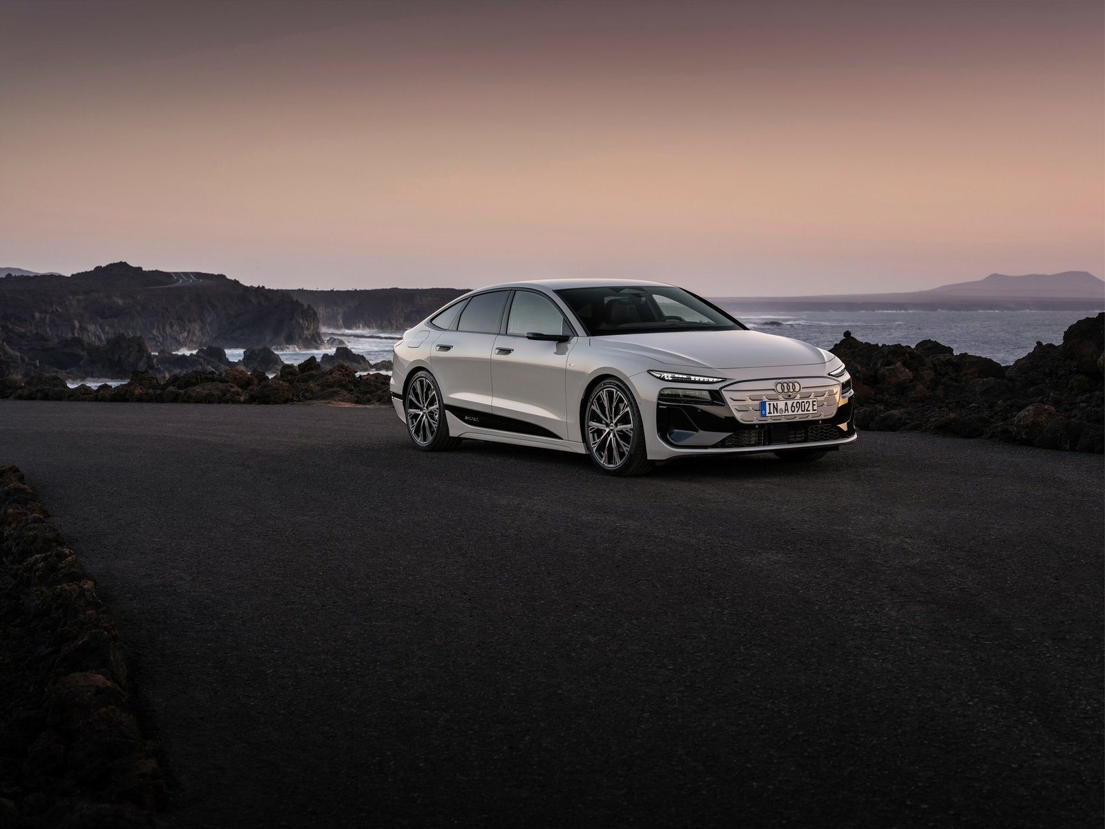 Audi A6 Sportback e-tron'un deniz kıyısındaki kayalıklar önünde duran beyaz bir örneği