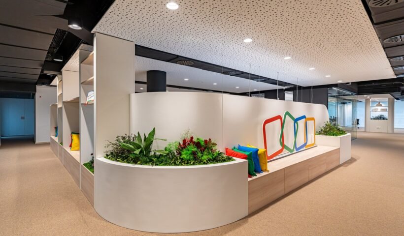 Bitki duvarı ve renkli bir logo detayıyla tasarlanmış modern bir ofis koridoru