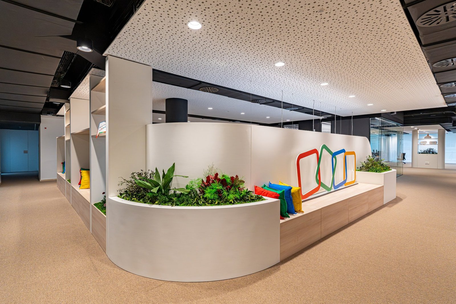 Bitki duvarı ve renkli bir logo detayıyla tasarlanmış modern bir ofis koridoru